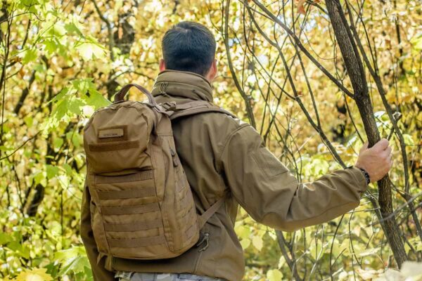 Rear view of man in the woods wearing a tactical backpack Rear view of man in the woods wearing a tactical backpack
