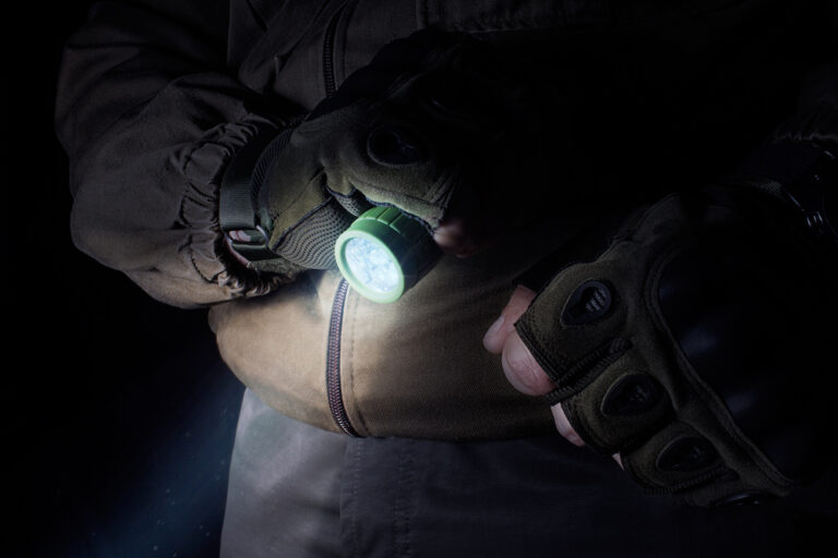 Man holding a tactical flashlight in the dark