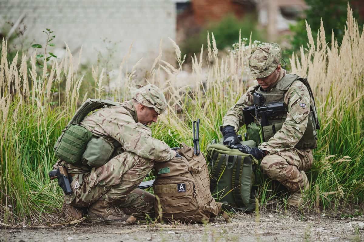 Two military officers packing their tactical backpacks Two military officers packing their tactical backpacks