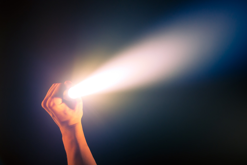 Black tactical flashlight with light turned on Black tactical flashlight with light turned on