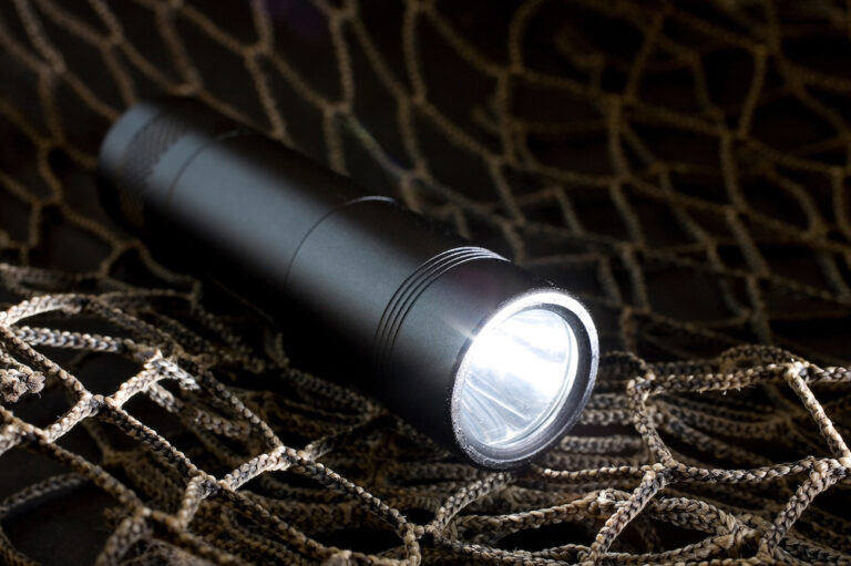 Black tactical flashlight suspended in net Black tactical flashlight suspended in net